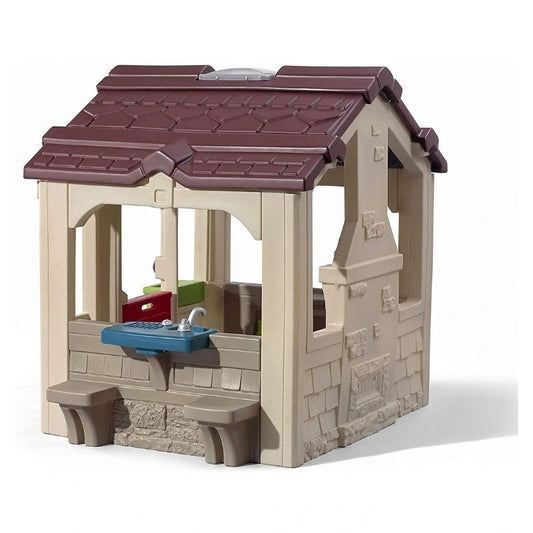 kids outdoor playhouse Qatar -A beige and brown plastic playhouse designed to look like a charming cottage with a kitchen and sink area, suitable for children's play.