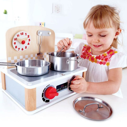 Best toy shop in Qatar – child playing with Hape 2 In 1 Kitchen & Grill Set, cooking with pot and pan, available to buy kids toys online in Qatar from the best online toy shop with toy delivery service in Qatar.