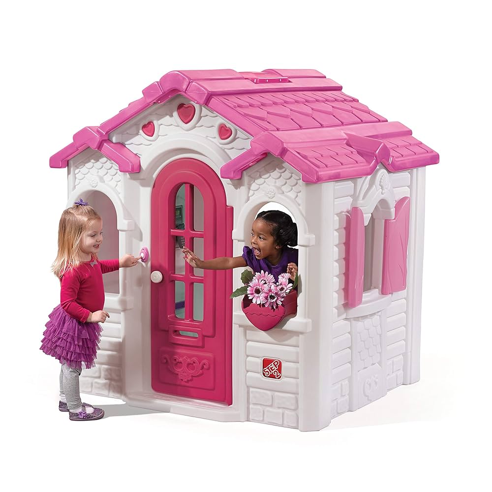 kids outdoor playhouse Qatar -Children playing with a pink and white toy house on a white background